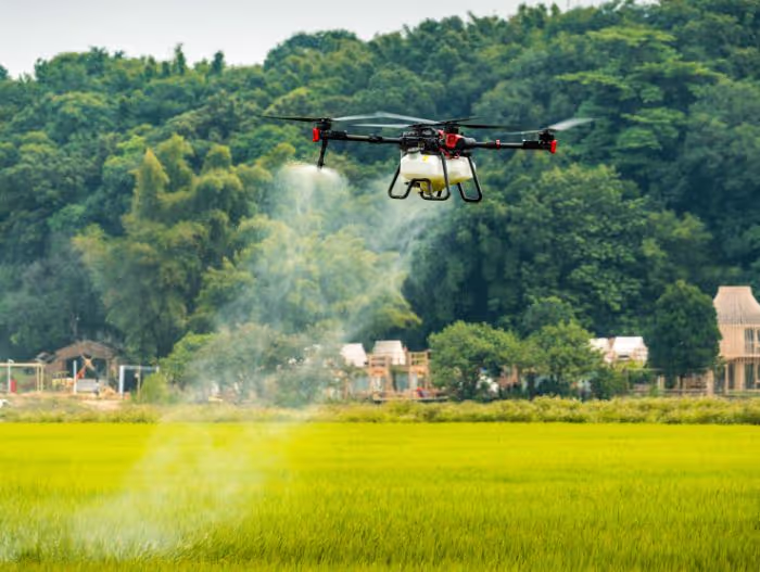 Agricultural drone spraying across a green crop field